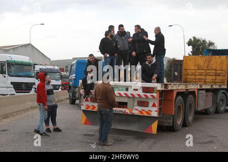 (220113) -- TRIPOLIS, 13. Januar 2022 (Xinhua) -- LKW-Fahrer blockieren die Straße von Tripolis nach Beirut während einer Protestaktion am Eingang nach Tripolis, Libanon, am 13. Januar 2022. Die Libanesen veranstalteten am Donnerstag einen landesweiten Protest gegen steigende Preise und sich verschlechternde Lebensbedingungen, die durch die langfristige Wirtschaftskrise verursacht wurden. Fahrer und Bürger gingen auf die Straßen der Hauptstadt Beirut, Tripolis, Khalde und anderer Städte, parkt ihre Autos mitten auf den Straßen und verbrennt Staubkörbe, um die Hauptstraßen zu blockieren. (Foto von Khaled Habashiti/Xinhua) Stockfoto