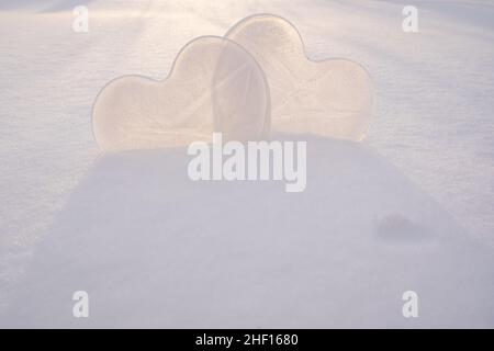 Zwei Herzen - ein Symbol der Liebe, aus Eis, im Schnee, in den Strahlen der Sonne. Valentinstag. Romantisches Konzept. Speicherplatz kopieren. Stockfoto