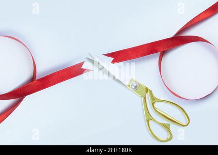 Große Öffnung, Goldschere schneidet rotes Seidenband vor weißem Hintergrund, Draufsicht, Banner, Kopierraum. Stockfoto