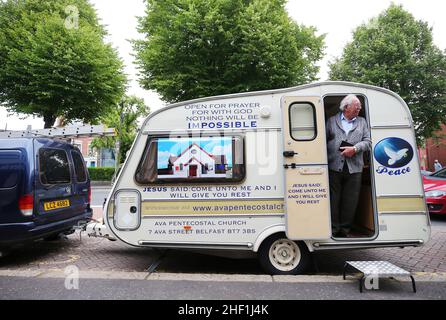 Ein religiöser christlicher Pastor stellte sich vor, wie er seine Straßenevangelisierung mit seiner Karawane auf der Ormeau Road im Süden von Belfast, Nordirland, leitete. Stockfoto