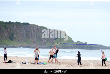 Im Sommer genießen die Menschen die warme Sonne und spielen Volleyball am Strand von Whitepark Bay, Co. Antrim, Nordirland. Stockfoto