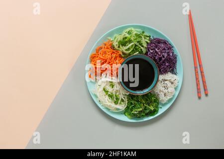 Hausgemachte vegetarische Poke-Schüssel frische rohe Karotten, Rotkohl, Gurke, Reis, essbare Algen mit Sojasauce, Ernährung, gesunde Lebensmittel. Draufsicht, Nahaufnahme Stockfoto