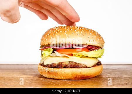 Der Burger in der Hand des Küchenchefs, Koch bereitet Hamburger zu und bereitet sie zu. Stockfoto