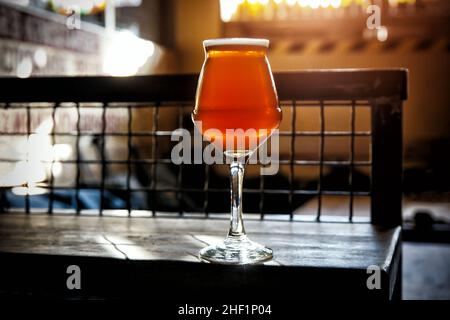 Glas auf einem dünnen Stiel aus kunstvoll gefertigtem Ale auf einer Holztischbar Stockfoto