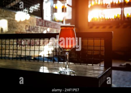 Glas auf einem dünnen Stiel aus kunstvoll gefertigtem Ale auf einer Holztischbar Stockfoto