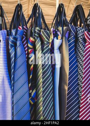 Große Auswahl an bunten Krawatten hängen in den Verkauf auf dem Straßenmarkt. Viele verschiedene Muster bunte Krawatten hängen auf Kleiderständer. Farbe Stockfoto