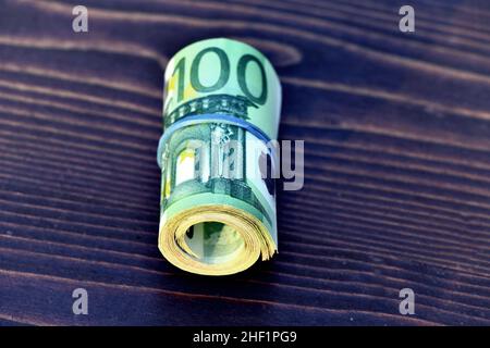 Rolle von 5000 Euro in 100-Euro-Banknoten isoliert auf Holzhintergrund Stockfoto