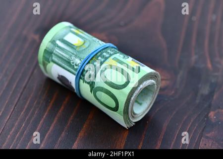 Rolle von 5000 Euro in 100-Euro-Banknoten isoliert auf Holzhintergrund Stockfoto