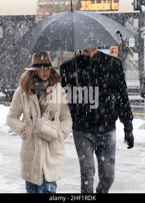 Belgrad, Serbien - 11. Januar 2022: Zwei junge Menschen, die an einem verschneiten Wintertag in der Stadt unter einem Regenschirm spazieren Stockfoto