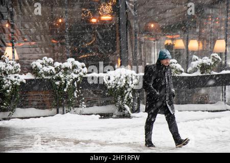 Belgrad, Serbien - 11. Januar 2022: Ein Mann, der an einem verschneiten Wintertag in der Stadt vor einem Restaurant läuft Stockfoto