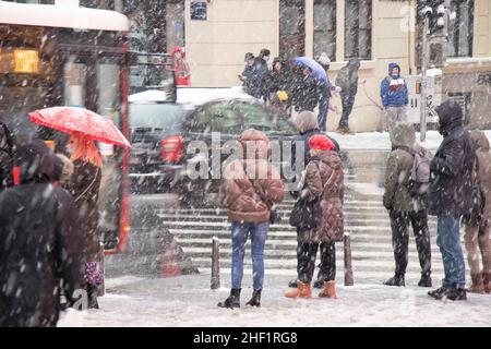 Belgrad, Serbien - 11. Januar 2022: Menschen warten an einer Kreuzung auf einer verschneiten Stadtstraße während eines starken Schneefalls Stockfoto