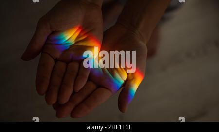 Regenbogenstrahl auf der Hand einer Frau. Stockfoto