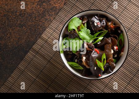 Chinesische eingelegte Baum schwarz Muer Pilze in Schüssel auf braunem Hintergrund. Blick von oben. Chinesische und asiatische Küche. Stockfoto