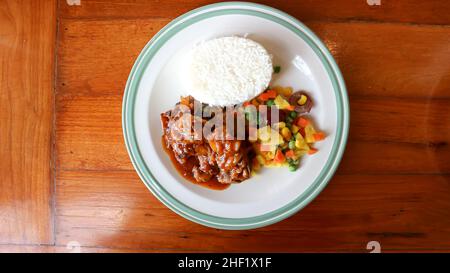 Geschmortes Schweinefleisch, Schweinefleisch mit Reis und Sauce oder Reis mit Schweinefleisch und Gemüse garniert Stockfoto