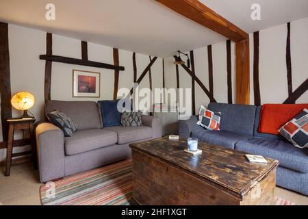 Clare, Suffolk - 27 April 2018: Charmantes kleines traditionelles Cottage-Wohnzimmer mit zwei Sofas und zahlreichen freiliegenden Holzbalken Stockfoto