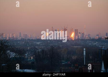 WIMBLEDON, LONDON, GROSSBRITANNIEN. 13. Januar 2022. Die Skyline von London und die Gebäude des Finanzdistrikts bei Sonnenuntergang in goldenem Abendlicht. Kredit: amer ghazzal/Alamy Live Nachrichten Stockfoto