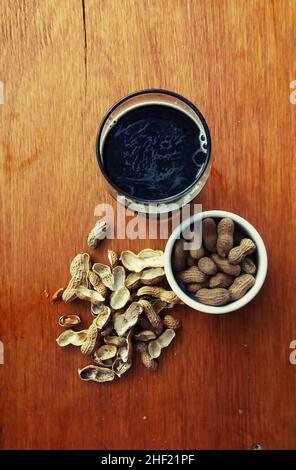 Schwarzes Craft-Bier mit Erdnüssen auf Holztisch Stockfoto