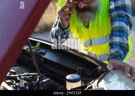 Hispanic sprach am Telefon, um einen Mechaniker zu bitten, sein kaputtes Auto auf der Straße zu reparieren Stockfoto