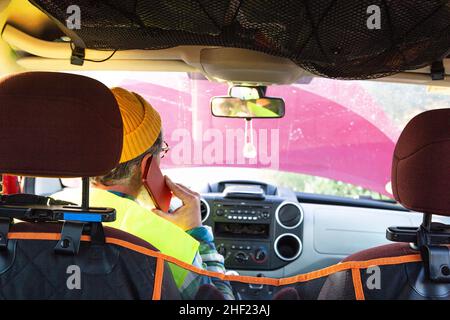 Mann in der Kabine des beschädigten Fahrzeugs telefoniert mit Pannenhilfe Stockfoto
