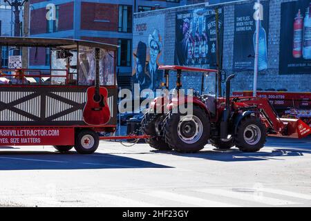 Nashville, Tennessee, USA - 7. November 2021: Die Tour-Bar wird von einem Traktor gezogen und nimmt einen Anhänger mit touristischen Werbeschildern an Gebäuden in der Altstadt. Stockfoto