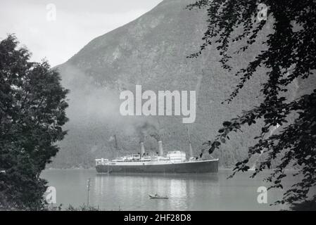 Historisches oder Vintage Schwarz-Weiß-Bild oder Monochromfoto eines frühen Dampfschiffs oder Dampfschiffs in einem morwegischen Fiord oder Fjord Norway 1938 Stockfoto