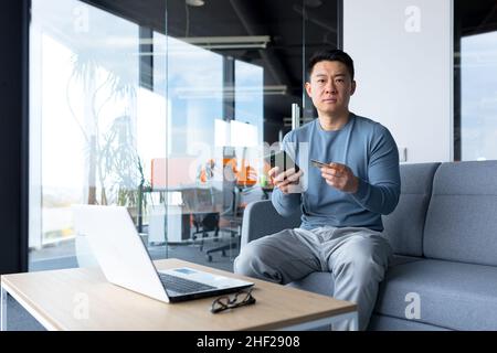 Ängstlich asiatische versuchen, Online-Zahlung per Kreditkarte und Telefon, Geschäftsmann arbeiten im Büro, Bank-Antrag Fehler zu machen Stockfoto