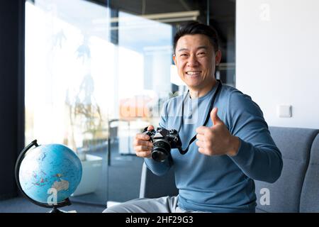 Porträt eines asiatischen Fotografen, glücklicher, männlicher Tourist-Blogger, arbeitet im Home Office, bloggt über Reisen und lehrt Fotografie Stockfoto