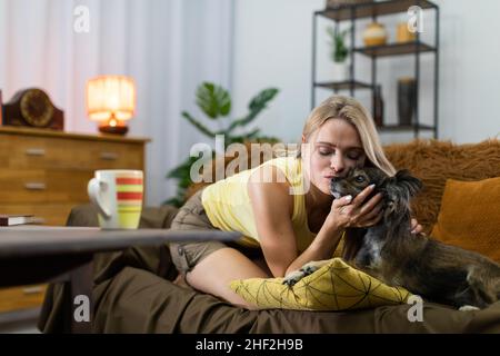 Ein junges Mädchen küsst die Schnauze ihres Hundes. Ein Wohnzimmer in einem Haus. Multirassischer Hund. Stockfoto