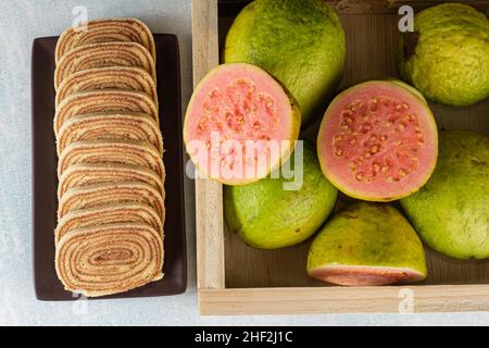 Geschnittener Bolo de rolo (Rollkuchen) neben einer Schachtel mit guavas top-Ansicht. Stockfoto