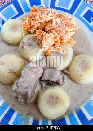 Polnische Dampfhefeknödel oder kluski na Parze können mit Fleisch und Soße oder in Butter sautiert und mit Zucker zum Dessert bestreut serviert werden. Stockfoto