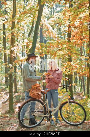 Junges Hipster-Paar, das ein romantisches Date im Wald hat und in der Nähe des Fahrrads gegeneinander steht. Erste wirklich ernste Beziehung. Erstes Datum Stockfoto