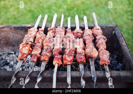 Grill auf dem Grill. Kebab auf Spießen, die im Freien kochen. Schaschlik an Spieße an der frischen Luft kochen. Stockfoto