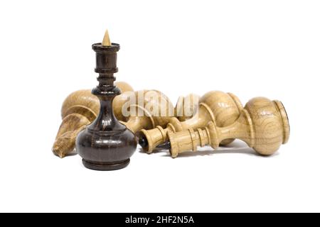 Schachfiguren isoliert auf weißem Hintergrund. Der schwarze Schachkönig steht über den liegenden weißen Stücken. Sieg und Niederlage Konzept. Stockfoto
