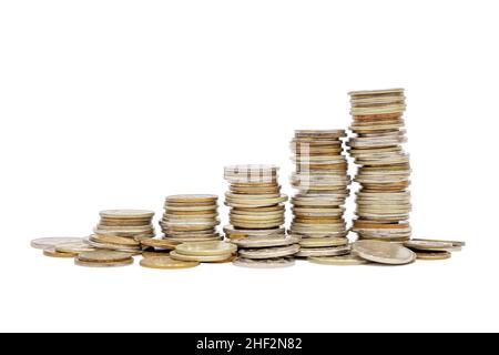 Fünf Stapel und Haufen verstreuter Münzen isolieren sich auf weißem Hintergrund. Konzept für das Geldwachstum. Bankwesen, Finanzen, Währung. Stockfoto