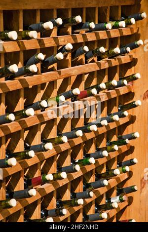 Geöffnete Weinflaschen in Holzregalen im Restaurant gestapelt. Viele Flaschen mit Korken. Gießen Sie Wein auf Bestellung. Stockfoto