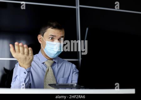 Schockierter Mann mit Gesichtsmaske, der auf das Notebook-Display schaute. Büroangestellte enttäuscht oder überrascht von einem unerwarteten Fehler auf dem Computergerät Stockfoto