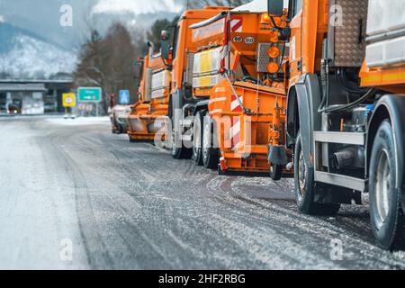 Liptovsky Hradok, Slowakei - 12. Februar 2020: Gruppe von hellorangen Straßenmeisterwagen mit Eisensalz, die sich im Winter vorbereiten, Schneekoje Stockfoto