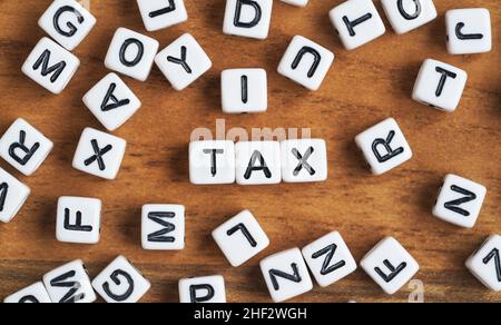 Kleine weiße und schwarze Perlenwürfel auf Holzbrett, Buchstaben in Mittelbuchstabe STEUER Stockfoto
