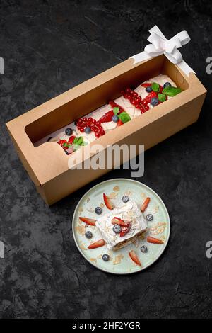 Meringuerolle mit Erdbeeren, Blaubeeren, Himbeeren und Preiselbeeren. Dessert mit frischen Beeren auf einem schwarzen Tisch dekoriert. Stockfoto