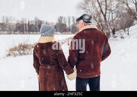 Ältere Familienpaare tanzen bei schneebedecktem Winterwetter im Freien. Ältere Menschen, die Spaß haben. Valentinstag Liebe Stockfoto