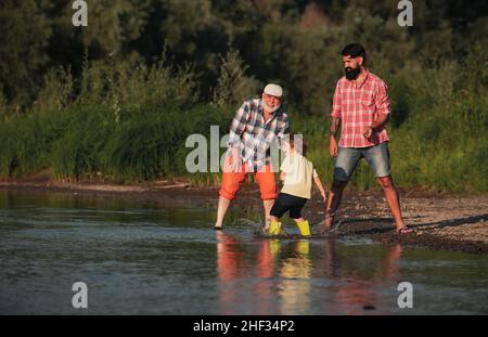 Familie in drei Generationen. Mit Papa und Großvater Steine überspringen. Drei verschiedene Generationen alt: Großvater Vater und Kind Sohn zusammen. Stockfoto