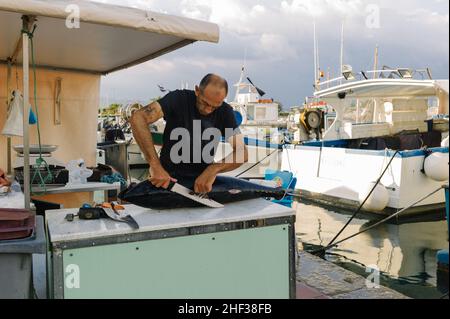 Fischer schneiden und bereiten nachhaltig frisch gefangenen Thunfisch auf seinem Stall im kleinen französischen Fischereihafen Sanary sur Mer an der Cote d' Azur in Südfrankreich zu. 2014. Stockfoto