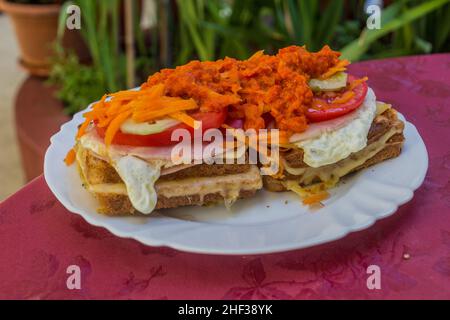 Essen in Bosnien und Herzegowina. Toast mit Gemüse, Schinken, Ei, Käse und Ajvar Stockfoto