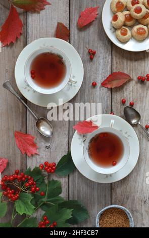 Autumn Flat Lay Komposition. Zwei Tassen Tee, trockene Blätter, rote Beeren auf Holz, rustikalen Hintergrund. Stockfoto