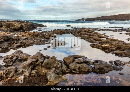 Sonnenuntergang mit dramatischen Himmel an der felsigen Küste in Tenesar, Lanzarote Stockfoto