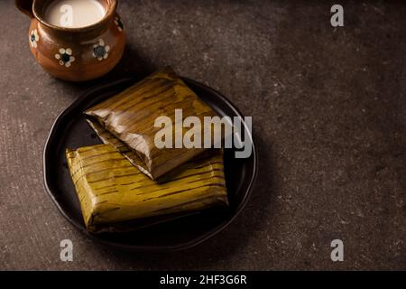 Prähispanische Gericht typisch für Mexiko und einige lateinamerikanische Länder. Maisteig in Bananenblätter gewickelt. Die Tamales werden gedämpft. Stockfoto