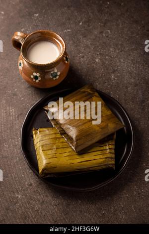 Prähispanische Gericht typisch für Mexiko und einige lateinamerikanische Länder. Maisteig in Bananenblätter gewickelt. Die Tamales werden gedämpft. Stockfoto