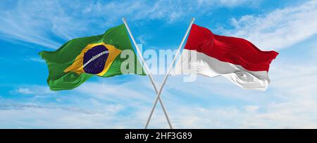 Gekreuzte Nationalflaggen Brasiliens und die Flagge von Monaco winken im Wind bei bewölktem Himmel. Symbolisiert Beziehung, Dialog, Reisen zwischen zwei Ländern. Stockfoto