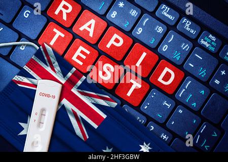 COVID-19 Schnelltest-Kit für positive Antigene auf Gesichtsmaske mit australischer Flagge auf Computertastatur. Konzept der Heimnutzung Covid Selbsttests in Australien. Stockfoto