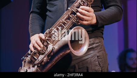 Saxophonist bei einem Konzert spielt Saxophon. Es ist dunkel Stockfoto